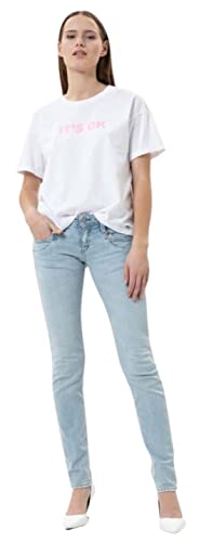 Modische junge Frau trägt Herrlicher Piper Slim Jeans aus Bio-Baumwolle, kombiniert mit einem weißen T-Shirt und eleganten hochhackigen Schuhen, ideal für einen nachhaltigen und stilvollen Look.